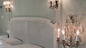 A bedroom with a white headboard, a glass bedside table, and two wall-mounted lamps. - B&B Mirabel (Bruges)
