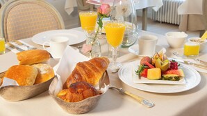 A breakfast setting with croissants, fruit, and orange juice on a table. - B&B Mirabel (Bruges)