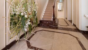 A grand hallway with a marble floor, a staircase, and a chandelier. - B&B Mirabel (Bruges)