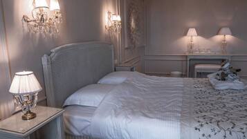 A bedroom with a large bed, two bedside lamps, a nightstand, and a small table with a lamp.