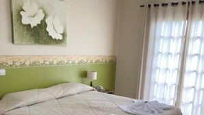 A double bed with a beige bedspread, two pillows, and two bedside tables with lamps. - Pousada Serra do Jordão (Campos do Jordão)