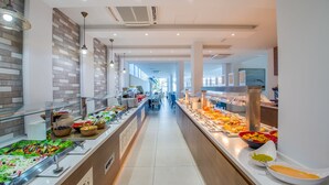 A buffet area with various food options, a long counter, and a modern interior design. - Stamatia Hotel (Ayia Napa)