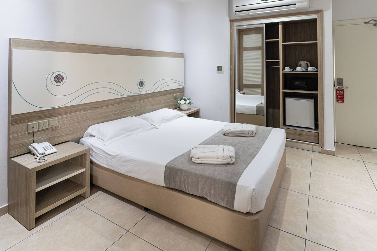 Ein Hotelzimmer mit einem großen Bett, einem Nachttischtelefon, einem Beistelltisch und einem Spiegel.