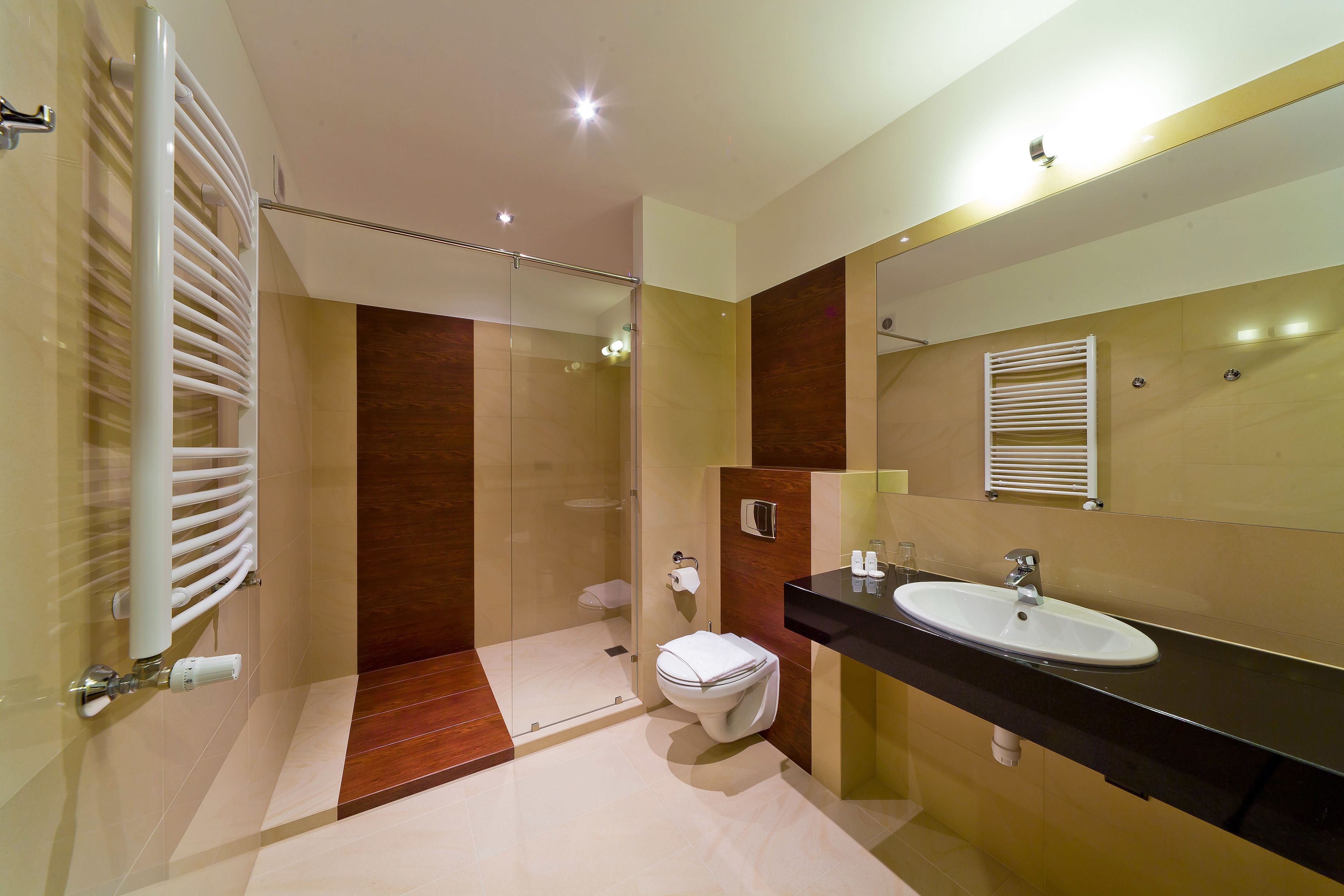 Une salle de bain moderne avec une douche à parois de verre, des toilettes et un lavabo surmonté d’un miroir.