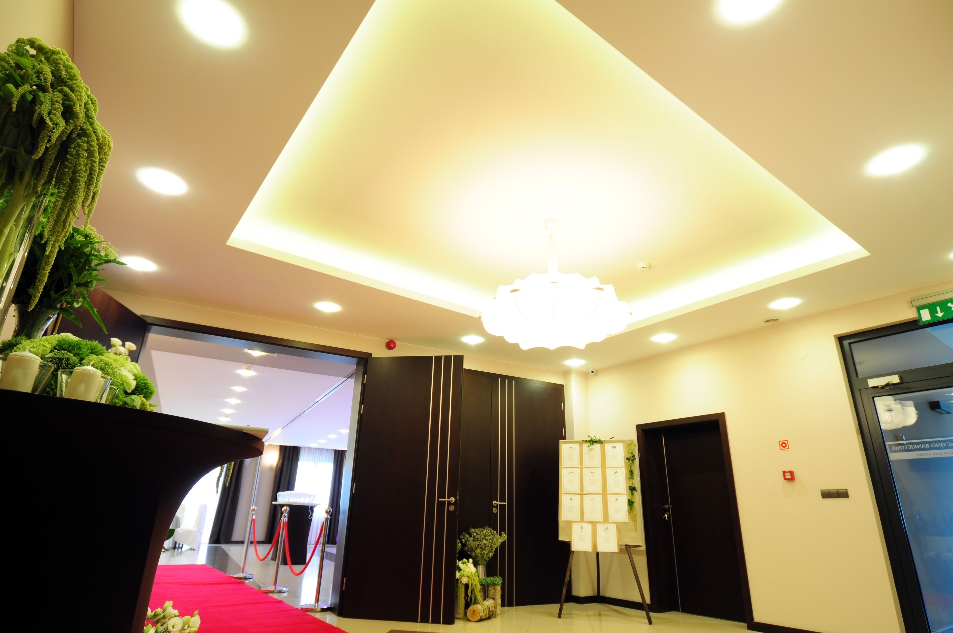 A hotel lobby with a red carpet, a large chandelier, and a reception desk.