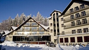Een hotel met een modern design, met een grote glazen gevel en een skilift op de achtergrond.