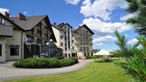 Een modern hotel met meerdere verdiepingen, een verzorgd gazon en terrasplekken.