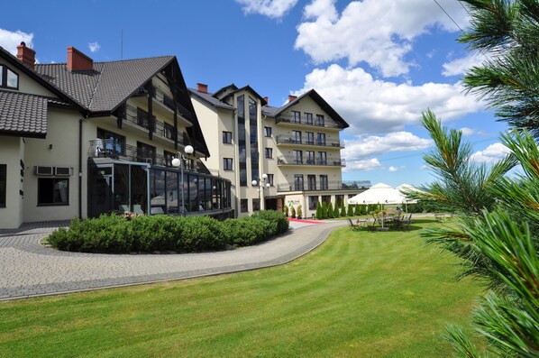 A modern hotel with multiple floors, a well-maintained lawn, and outdoor seating. - Hotel Zimnik Luksus Natury (Lipowa)