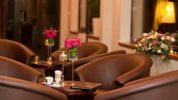 A dining area with leather chairs, a table with a teapot, cups, and a vase with flowers.