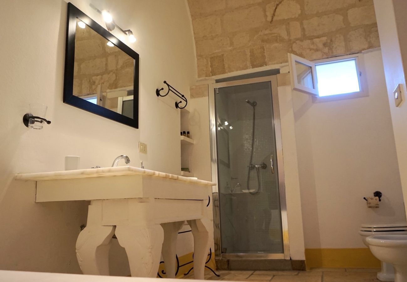 A bathroom with a white sink, a mirror, a shower, and a toilet.
