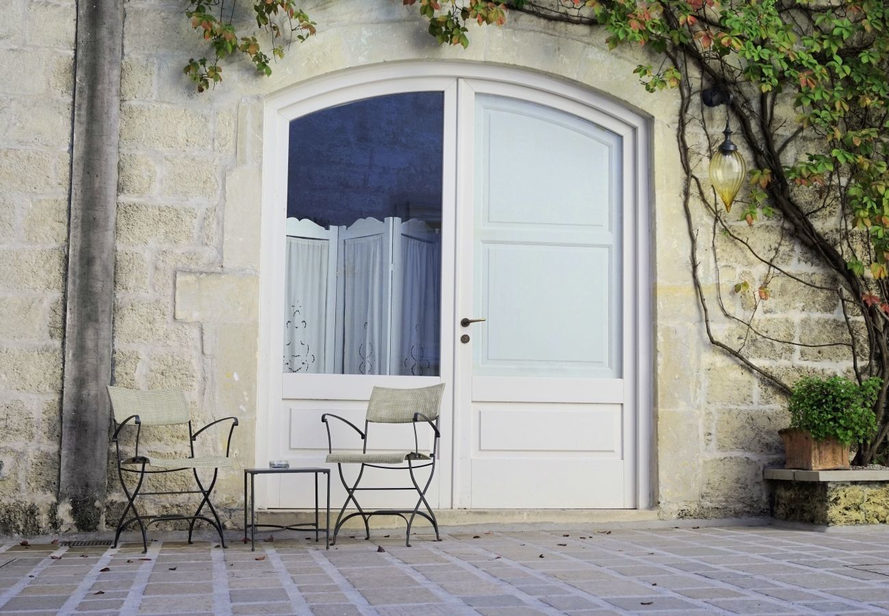 A white door with a glass panel, two metal chairs, and a small table outside a stone building.