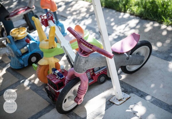 A toy motorcycle with a pink handlebar and a red seat, parked on a concrete surface. - Palazzo Guglielmo Albergo Diffuso (Ortelle)