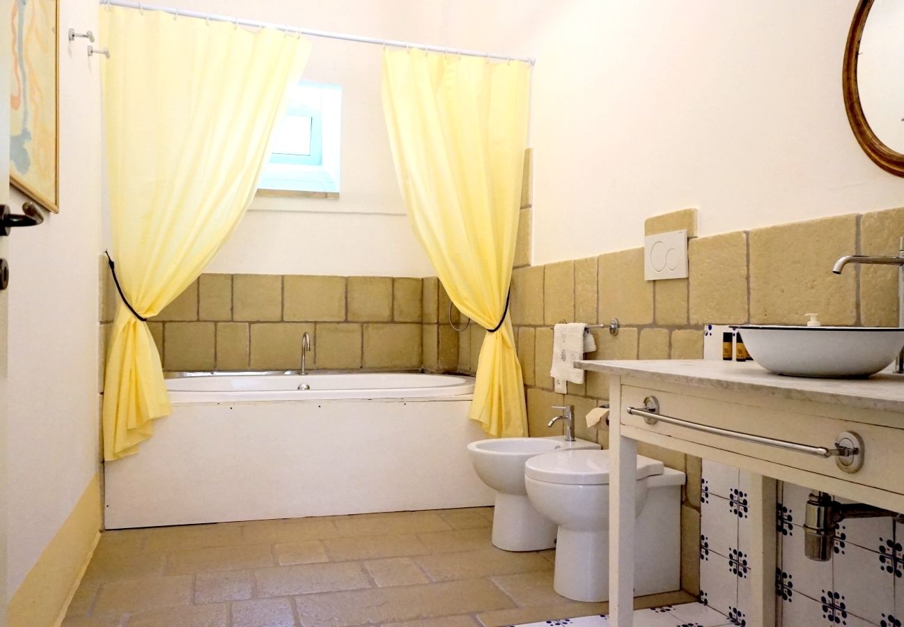 A bathroom with a bathtub, two toilets, and a sink with a basin.