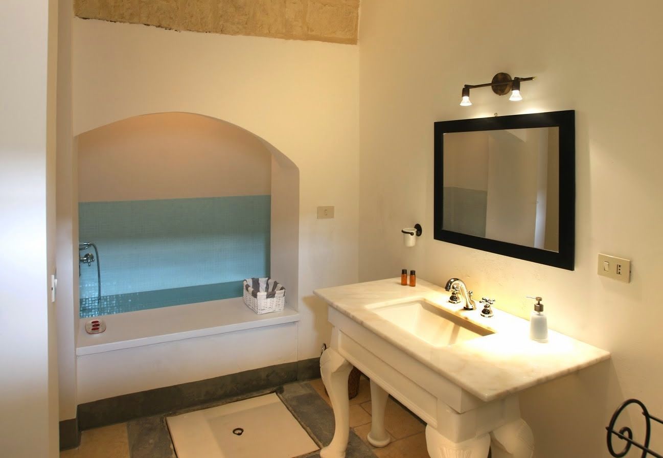 A bathroom with a bathtub, a sink, and a large mirror.