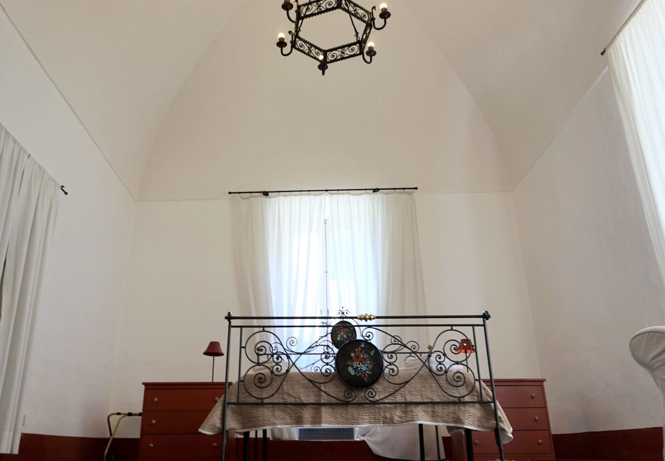 A room with a bed, a dresser, a lamp, and a chandelier.