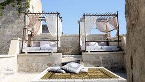 A rooftop terrace with two beds, each with a canopy, and a central area with a mat and pillows. - Palazzo Guglielmo Albergo Diffuso (Ortelle)