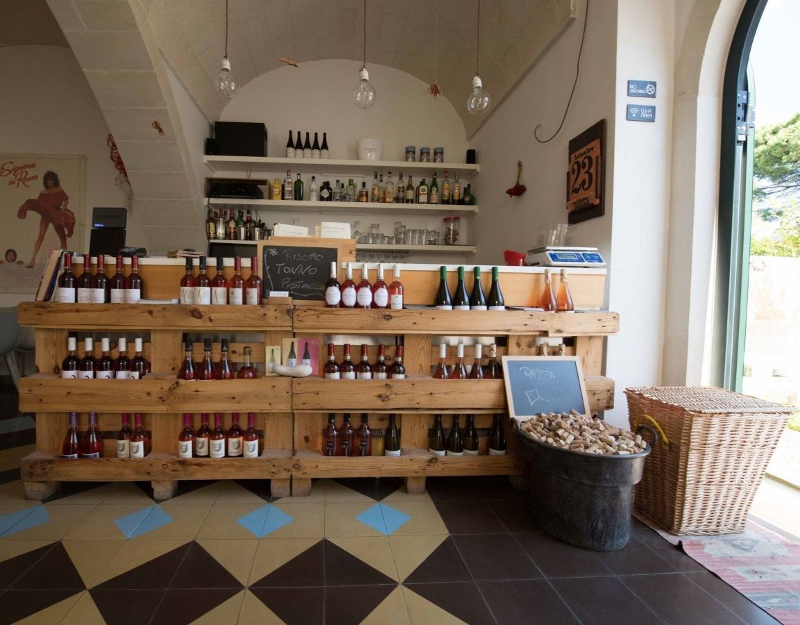 Una bodega con estantes de madera que exhiben varias botellas, un menú en pizarra y una cesta de mimbre.