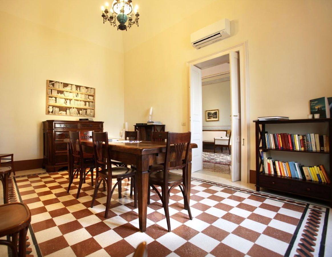 A dining area with a checkered floor, wooden furniture, and a bookshelf.