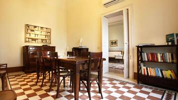 A dining area with a checkered floor, wooden furniture, and a bookshelf.