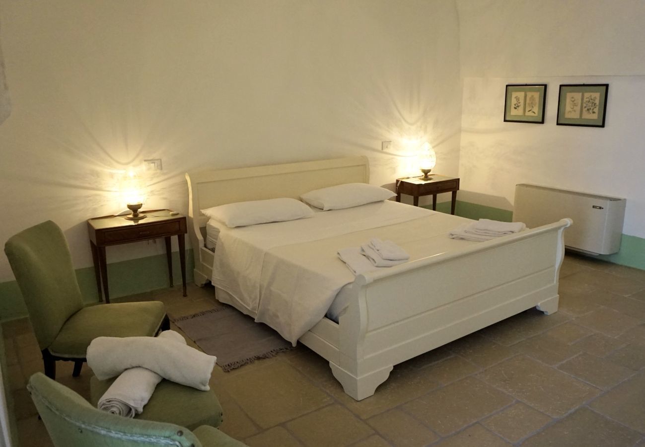 A bedroom with a single bed, two bedside tables, a chair, and a radiator.