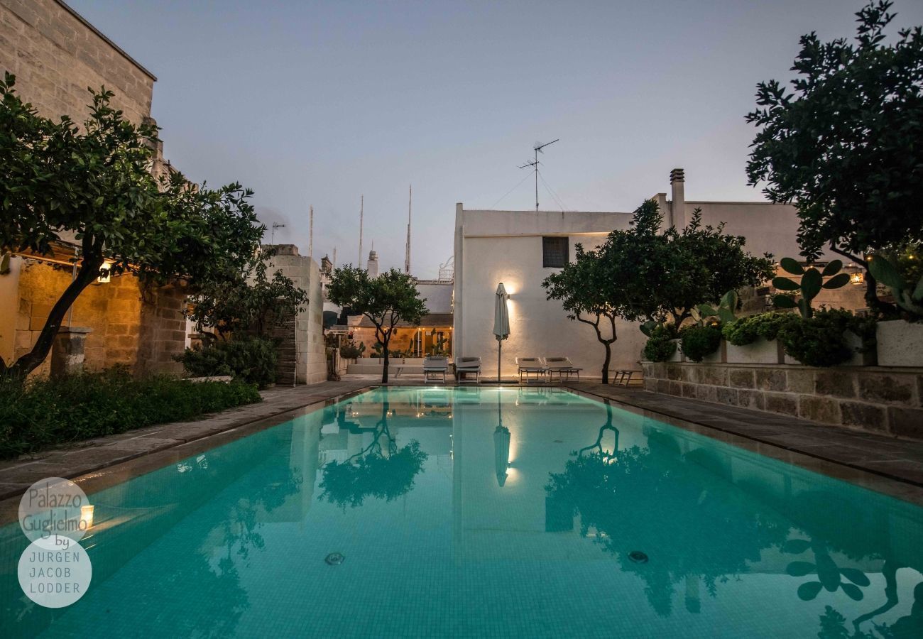 Una piscina con sillas de descanso y un edificio al fondo.