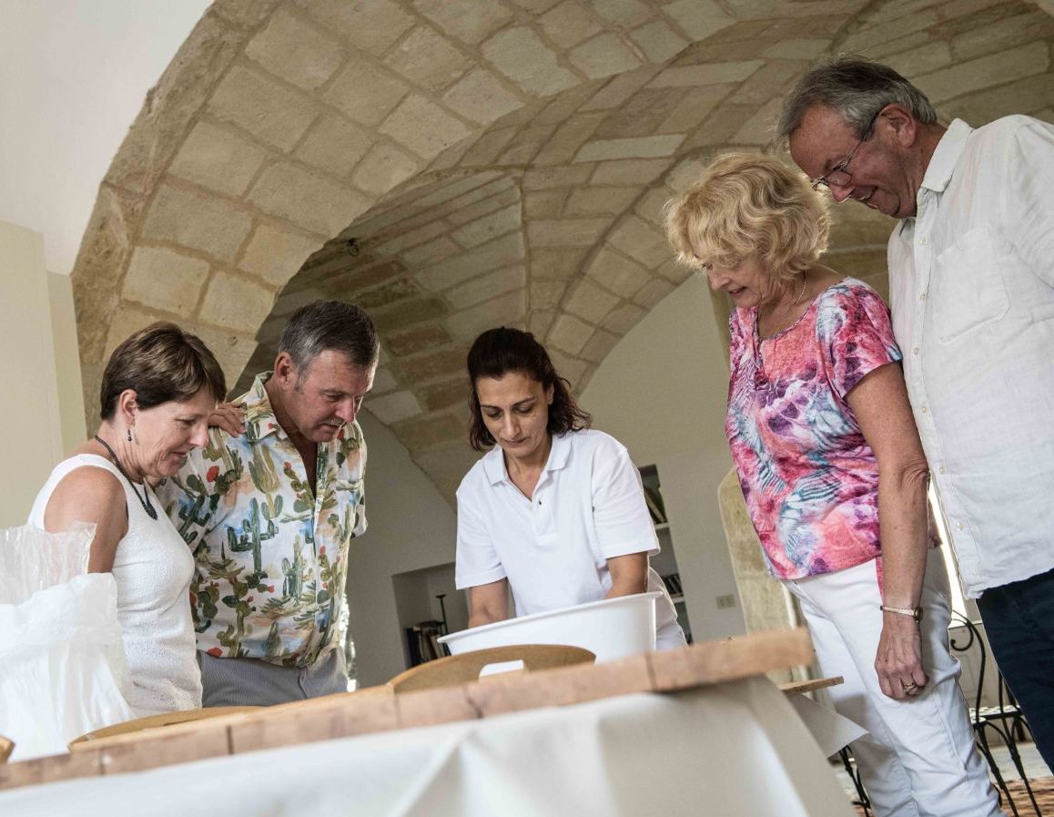 Een groep mensen rond een tafel in een ruimte met een stenen plafond en een praktische, eenvoudige indeling.