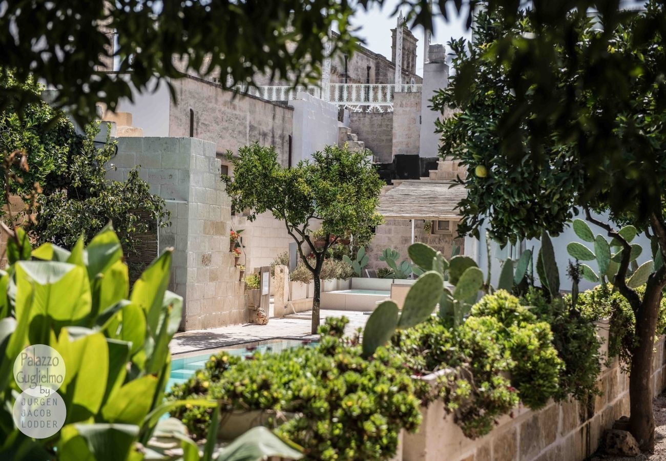 Une cour avec une piscine, des cactus et un mur en pierre.