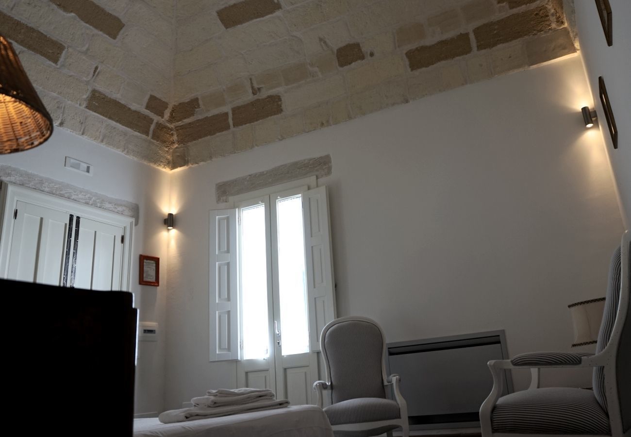 Una habitación con techo de ladrillo, dos ventanas con marcos blancos, un radiador y dos sillones tapizados.