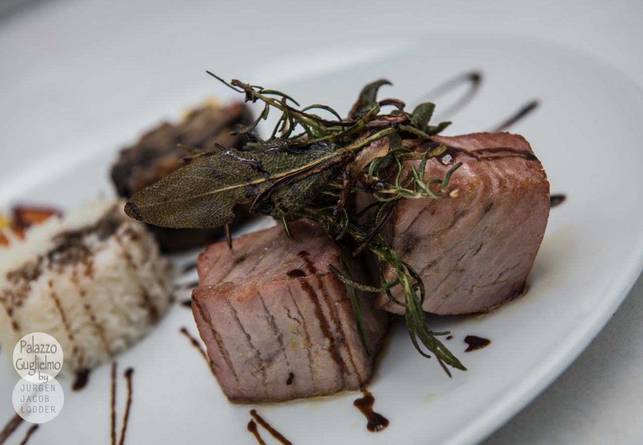Une assiette contenant un morceau de viande, peut-être du porc, et quelques herbes.