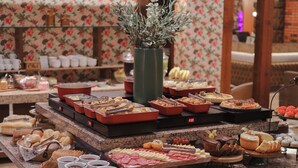A buffet with various food items and a clock on the counter. - Hotel Glamour da Serra (Gramado)