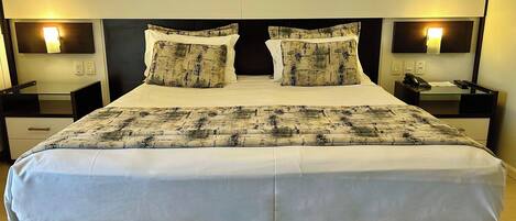 A double bed with a patterned bedspread, two bedside tables with lamps, and a telephone on one of the tables.