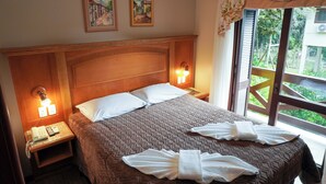 A hotel room with a large bed, two bedside lamps, a telephone, and two paintings on the wall. - Pousada das Papoulas (Gramado)