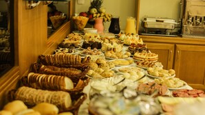 A buffet table with various food items and a pitcher of juice. - Pousada das Papoulas (Gramado)