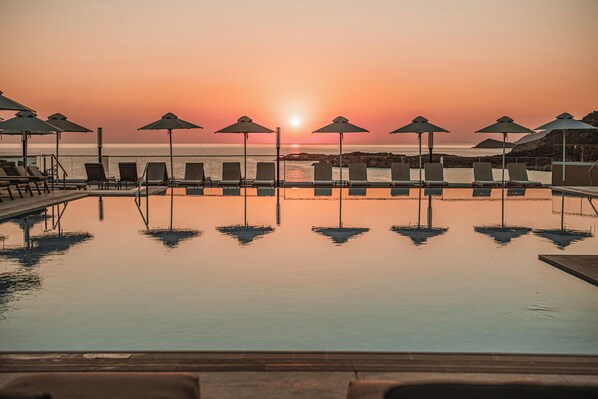 A poolside area with lounge chairs and umbrellas, overlooking the sea during sunset. - Mitsis Bali Paradise (Mylopotamos)