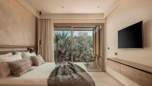 Une chambre à coucher avec un lit, un téléviseur fixé au mur et une porte-fenêtre coulissante donnant sur un balcon agrémenté de plantes.