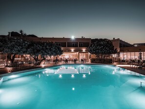 A swimming pool with a view of a building with multiple floors and outdoor seating areas. - Mitsis Bali Paradise (Mylopotamos)