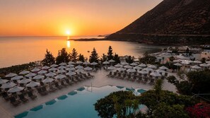 A resort with a pool, sun loungers, umbrellas, and a view of the sunset over the sea. - Mitsis Bali Paradise (Mylopotamos)