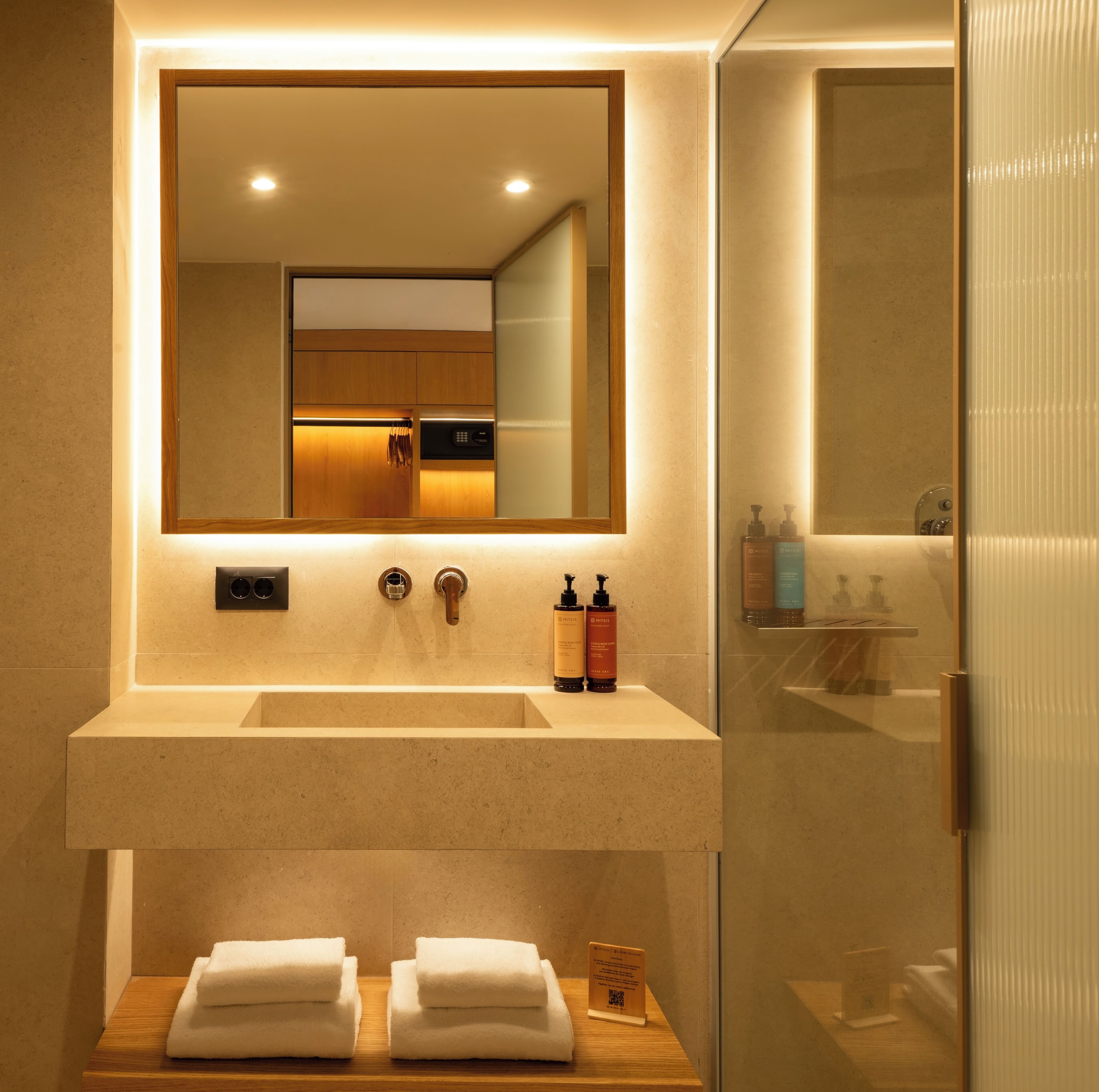 Une salle de bain moderne avec un grand miroir, un lavabo et une douche à parois de verre.