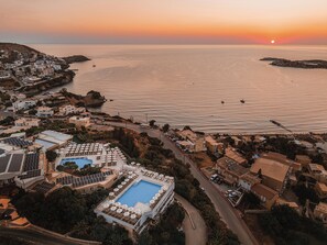 A resort with a swimming pool, multiple guest rooms, and a view of the sea at sunset. - Mitsis Bali Paradise (Mylopotamos)