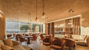 Un intérieur moderne comprenant différents espaces de détente, avec des canapés et des fauteuils, ainsi qu’un coin bar doté d’un comptoir.