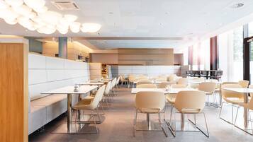 Un restaurante moderno con largas mesas comunitarias y cabinas, una pared de acento de madera e iluminación empotrada en el techo.