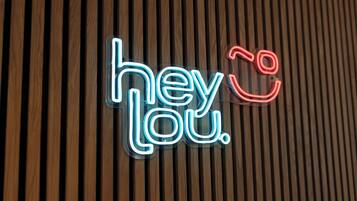 Un letrero de neón con el texto 'hey Lou' sobre un fondo de madera.
