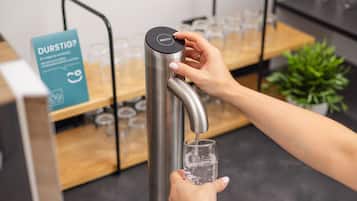 Una mano llenando un vaso con agua de un grifo moderno.