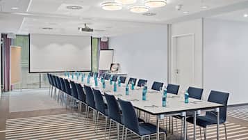 Uma sala de conferências com uma mesa comprida, cadeiras, um projetor e uma tela.