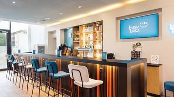 Eine Bar mit Theke, Barhocker, Flaschenregalen und einem Neonzeichen.