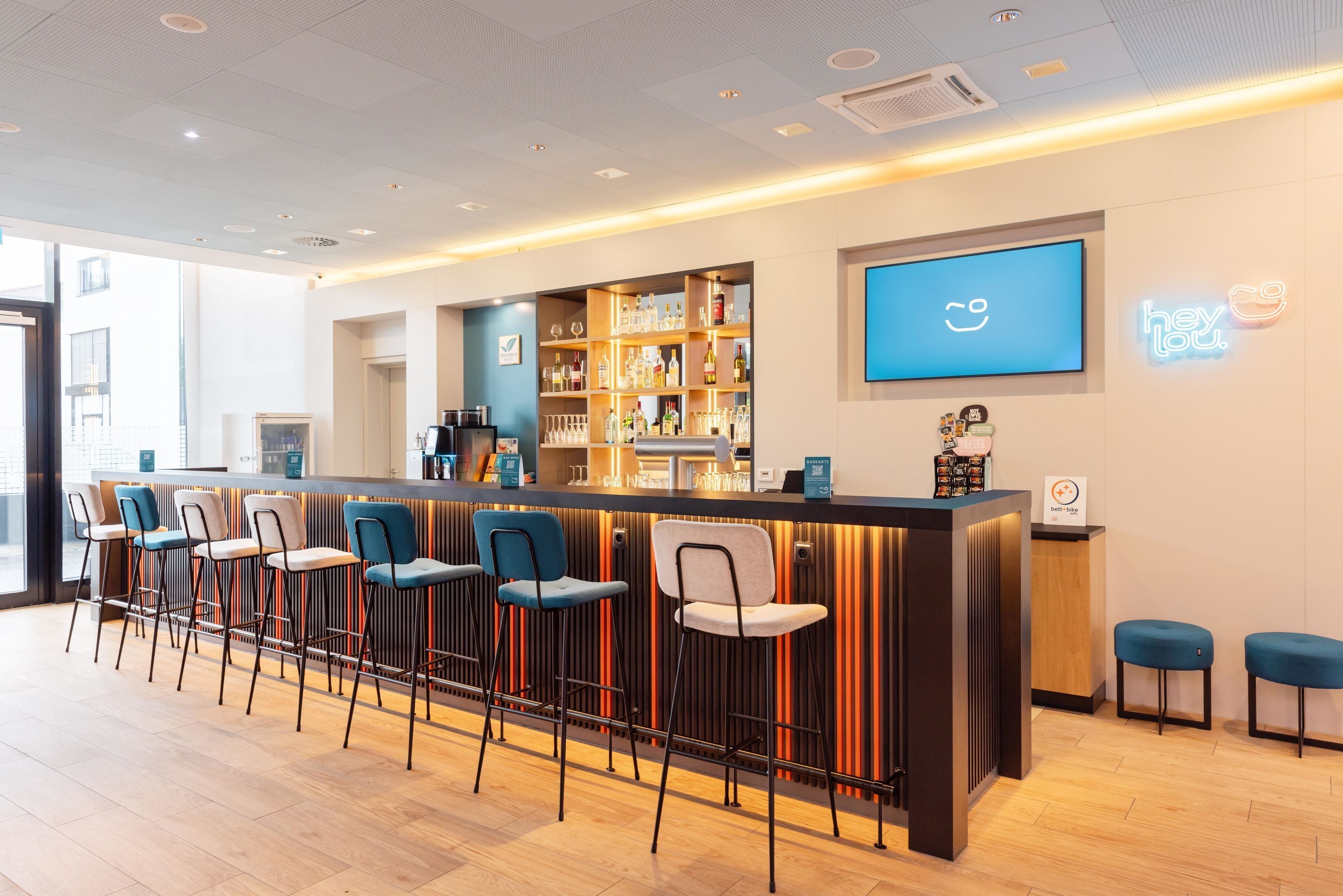 A bar area with stools, a counter, and a neon sign.