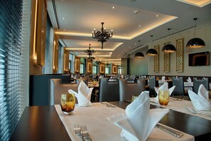 A restaurant with multiple dining tables, each set with white napkins, cutlery, and glasses. - Crowne Plaza Istanbul - Oryapark by IHG (Istanbul)