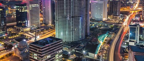 A cityscape with high-rise buildings, a dome structure, and a busy road with light trails.