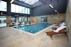 Una piscina techada, sillones reclinables de piscina