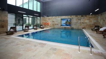 Een binnenzwembad, ligstoelen bij het zwembad